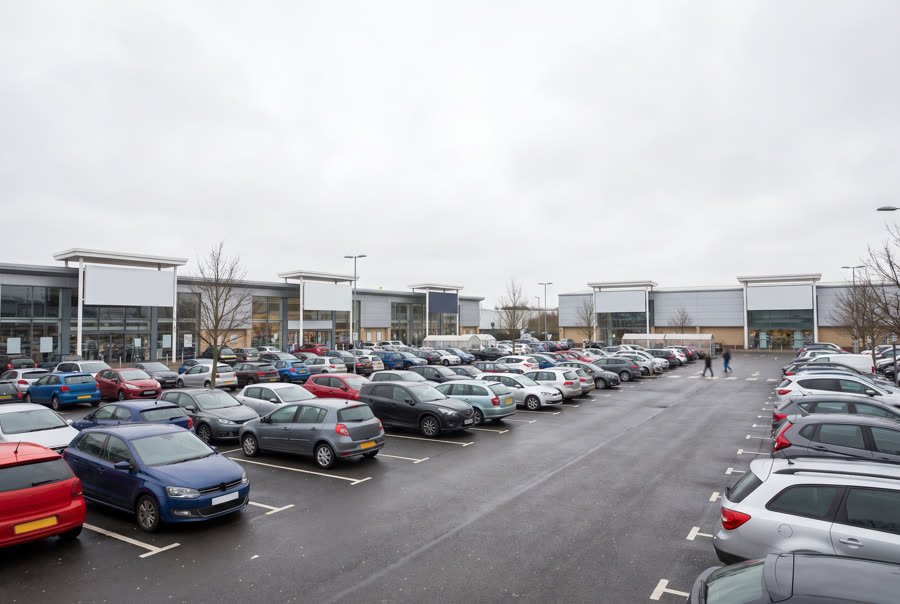 A busy UK retail park car park in daylight